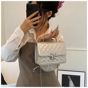 Détail du sac bandoulière argenté matelassé avec fermoir nœud et bandoulière chaîne