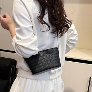 Model wearing a small black woven leather crossbody bag with a slim strap for daily style