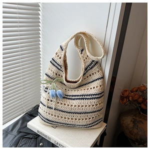 Detail of woven straw tote bag with blue stripes and decorative tulip flower charms