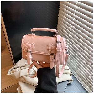Detail of pink glossy patent leather bag with bow buckles and adjustable shoulder strap