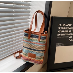 Détail du sac seau tissé à rayures multicolores avec poignées en cuir et étiquette