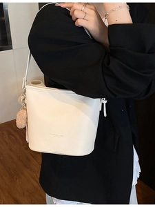 White litchi pattern leather bucket bag with shoulder strap and pompom keychain