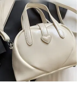 Close-up of cream bowling bag with heart embossing and 3D heart buckle detail