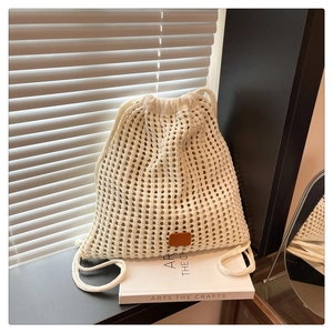 Detailed view of cream knit bucket backpack with hollow floral patterns and leather patch