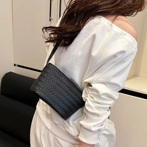 Close-up of black woven leather texture on a stylish square underarm bag for women