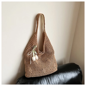 Detail of hand-woven straw tote bag with delicate white tulip and pearl charm accessory
