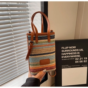 Détail d'un sac seau tissé à rayures colorées avec poignées et bandoulière en cuir