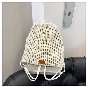 Detail of white knit drawstring backpack with hollow mesh pattern and leather logo patch