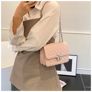 Détail du sac à bandoulière matelassé rose avec boucle nœud argentée sur le modèle