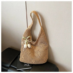 Close-up of handwoven straw tote with pearl chain and tulip charm decorations