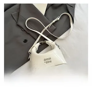 Detailed view of white crocodile pattern leather handbag on a grey suit jacket background