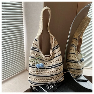 Close-up of beige crochet tote with black stripes and a blue tulip flower pendant