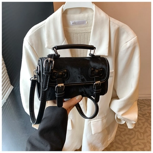 Detail of black crossbody bag with double buckle straps and silver hardware accents