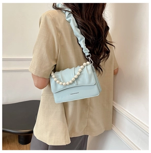 Detail of light blue pleated cloud bag with elegant pearl handle and fashion text