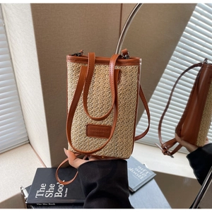 Détail d'un sac seau en paille tissée avec garniture en cuir brun et boucle en métal