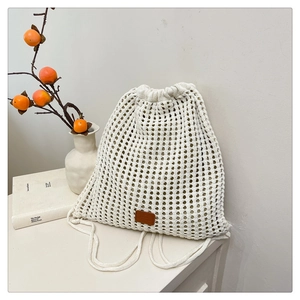 Detailed knit texture and brown leather label on cream crochet drawstring backpack