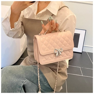 Détail du sac bandoulière rose matelassé avec boucle nœud argentée et bandoulière chaîne