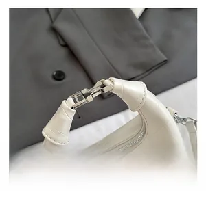 Detail of the white crocodile texture handbag with its elegant silver metal buckle and handle