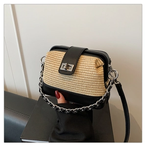 Detail view of woven straw texture and black leather contrast on a chain crossbody bag