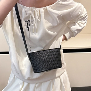Detail of black woven leather crossbody bag texture worn with white outfit