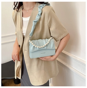 Detail of light blue pleated cloud bag featuring pearl handle and brand engraving