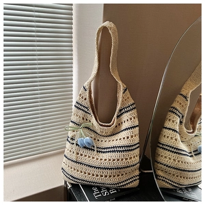 Detail of hand-woven straw tote bag with blue stripes and a tulip flower pendant decoration