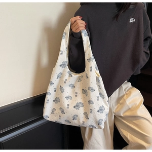 Detail shot of white canvas tote bag featuring blue goldfish print and wide shoulder strap