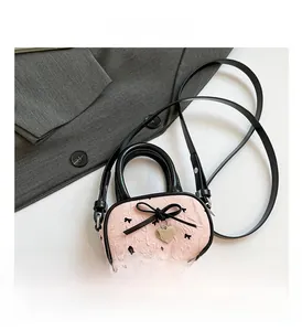 Dettaglio borsa rosa con fiocco, ciondolo a cuore e tracolla rimovibile su scrivania