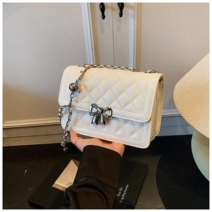 Détail du sac bandoulière matelassé blanc avec fermoir nœud argenté et bandoulière chaîne