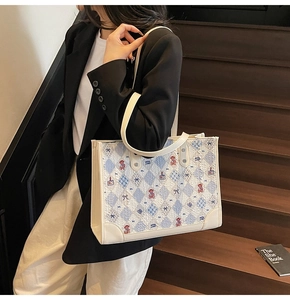 Détail du sac cabas à carreaux bleu clair avec imprimé ours sur des marches en bois
