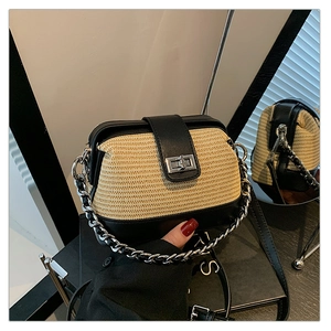 Detail of woven straw crossbody bag with black leather trim and silver chain