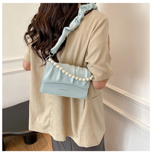 Detail of light blue pleated cloud bag with elegant pearl chain and fashion embossing