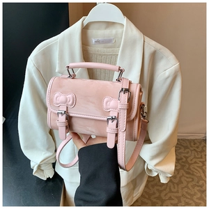 Pink mini crossbody bag with bow detail and twin buckles shown in a sweet college style