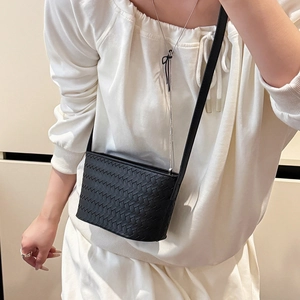 Detail of a black woven leather crossbody bag showcasing premium texture and minimalist aesthetic