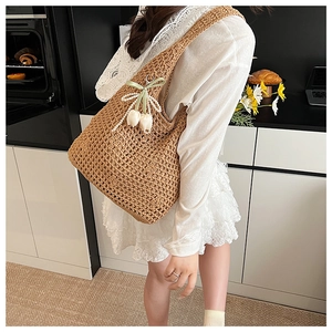 Close-up of woven straw shoulder bag featuring mesh knit and tulip pearl charms