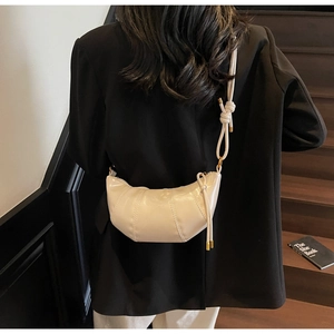 Detail of beige croissant bag with pleated texture and stylish knotted shoulder strap