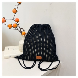 Detail of black knit drawstring backpack featuring mesh hollow patterns and leather logo