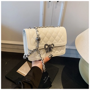 Détail du sac à bandoulière matelassé blanc avec boucle nœud argenté et chaîne perlée