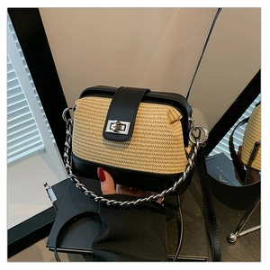 Close-up of a woven shell bag with black leather flap and silver chain shoulder strap