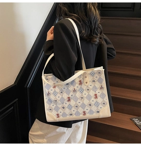 Sac fourre-tout à motif losanges bleus et ours porté par un mannequin en escalier