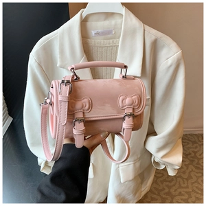 Detailed view of pink crossbody bag featuring dual decorative bows and fine PU leather texture
