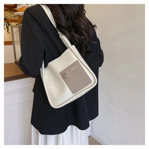 Detail of lychee textured leather shoulder bag with a brown zipper pocket and contrast design
