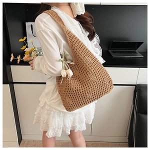 Detail of woven straw shoulder bag with white flower charm and pearl chain accent