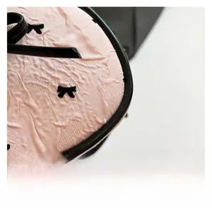 Dettaglio del tessuto plissettato rosa con ricamo a fiocco nero e bordo sulla borsa