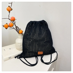 Close-up of black crochet knit bucket bag showing hollow floral texture and brown leather label