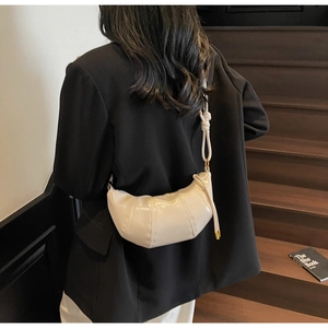 Detail of cream white croissant bag with stitched panels and knotted shoulder strap