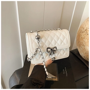 Vue détaillée du sac matelassé blanc avec fermoir nœud argenté et bandoulière chaîne