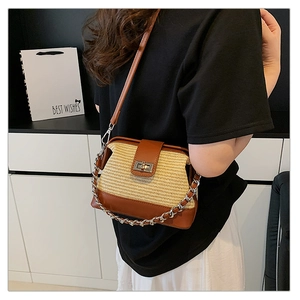 Detail of straw and brown leather crossbody bag with gold-tone metal twist-lock buckle