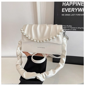 Detail of white pleated cloud bag featuring large pearl chain and leather wide strap
