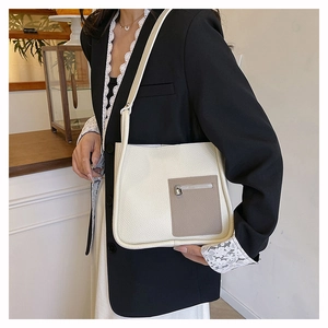 Close-up of beige lychee texture leather shoulder bag with contrast brown zipper pocket
